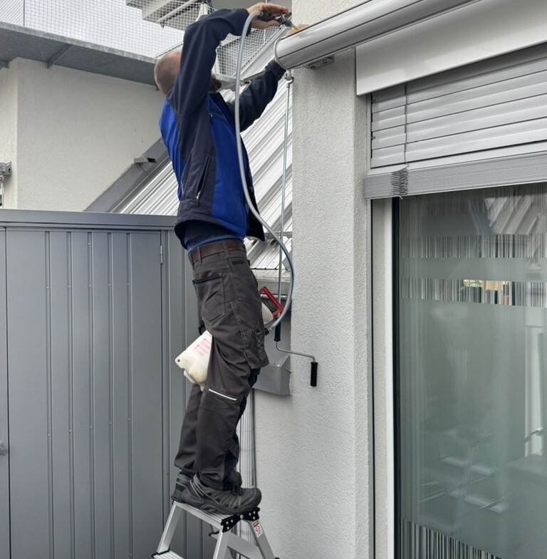 Un technicien &agrave; Cologny retire un nid de gu&ecirc;pes d&rsquo;un volet roulant, &eacute;quip&eacute; de mat&eacute;riel de s&eacute;curit&eacute; de Kammerjaeger.